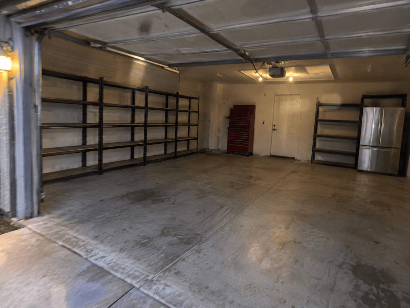 The garage cleared, leaving empty shelving, a tool chest and the refrigerator