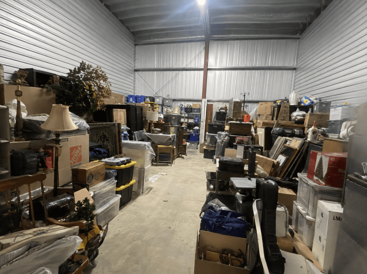 A storage unit stacked with furniture, boxes, lamps and framed art